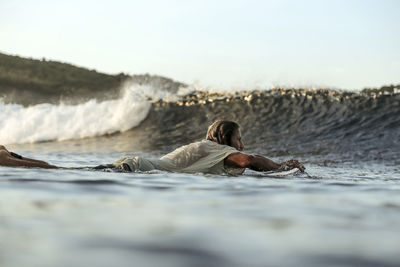 Surfer in sea at sunset, lombok, indonesia