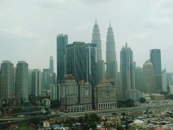 Skyscrapers in city against cloudy sky