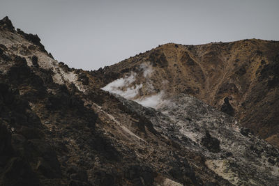 Low angle view of rocky mountains against clear sky