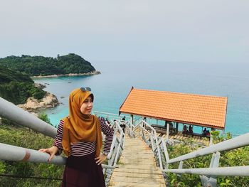 Woman standing by railing against sea