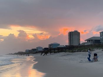 People on beach against sky during sunset