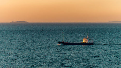 Boat sailing on sea against clear sky during sunset