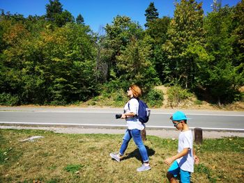 Side view of boy with mother walking on grassy field