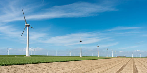 Wind turbines on field against sky