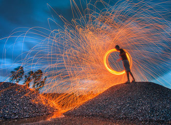 Man spinning wire wool at night