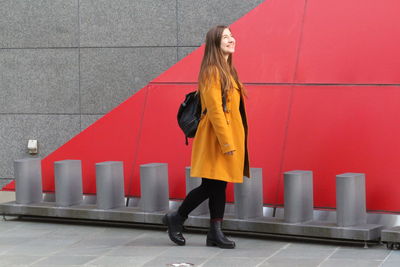 Full length of woman standing against red wall