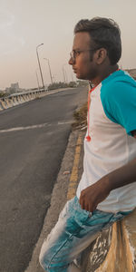 Boy standing on road against sky