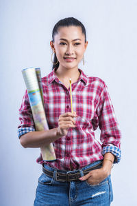 Portrait of young woman standing against white background