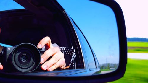 Reflection of man holding car on side-view mirror