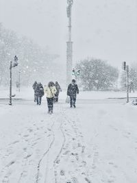 People walking on snow covered field during winter