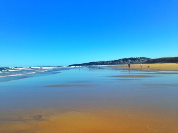 Scenic view of beach against clear blue sky