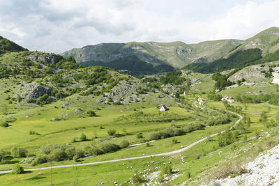 Scenic view of green landscape and mountains against sky