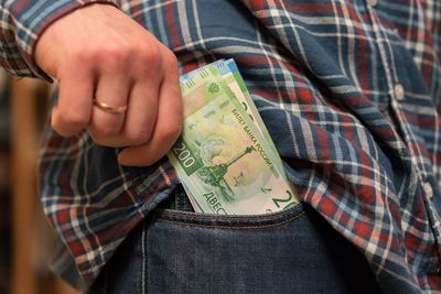 Midsection of man removing paper currency from pocket