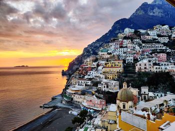 Panoramic view of sea and buildings against sky during sunset