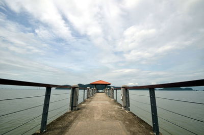 Walkway by sea against sky