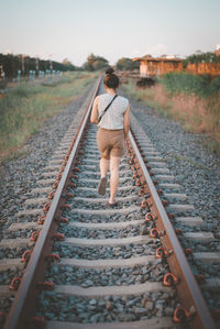 Rear view of woman walking on railroad track