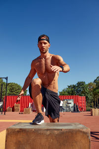 Portrait of young man exercising against clear blue sky