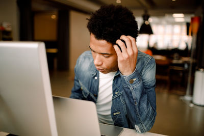 Worried male professional using laptop while sitting at office desk