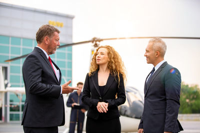 Business people standing by helicopter at airport