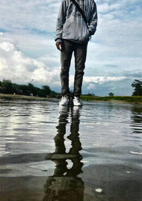 Low section of man standing in lake