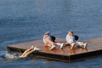 Artists performing on diving platform over lake