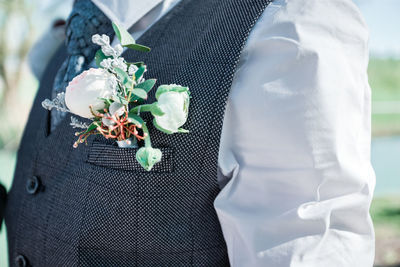 Midsection of bridegroom wearing flower