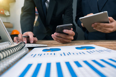 Midsection of man using smart phone on table