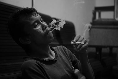 Young man smoking cigarette at home