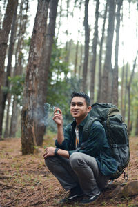 Young man sitting on tree trunk in forest