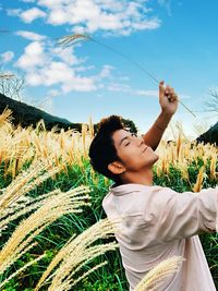 Smiling man standing amidst cereal plants on field