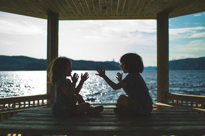 People sitting by sea against sky