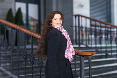 Young woman looking away while standing against railing