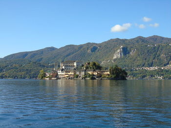 Scenic view of lake by buildings against blue sky