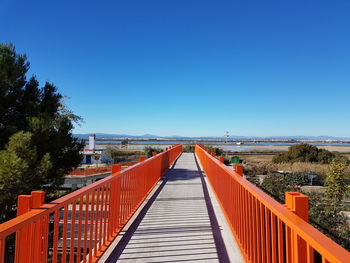 Footbridge over sea against clear blue sky