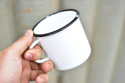 White metal enameled mug in the hands of a person
