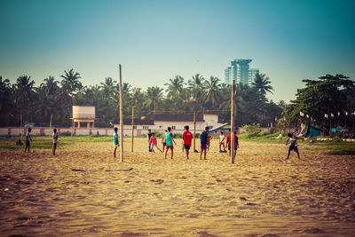 People playing soccer field against sky