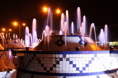 Illuminated fountains at park during night