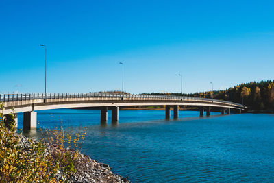Bridge over river against clear blue sky during autumn