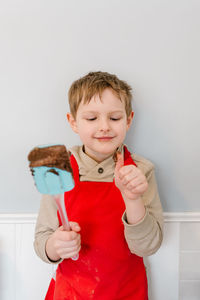 Smiling boy standing against red wall