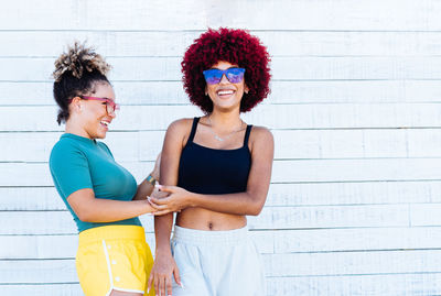 Smiling young woman standing against the wall