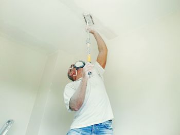 Man painting ceiling at home