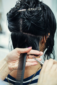 Cropped hands of hairdresser cutting hair in salon
