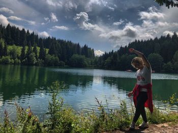 Woman standing by lake against sky