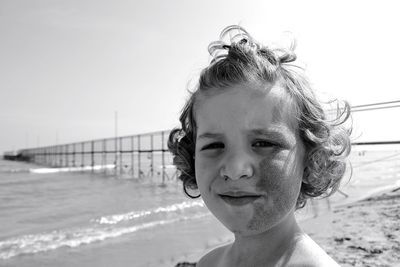 Portrait of messy girl at beach against sky
