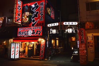 Information sign on illuminated street amidst buildings in city at night