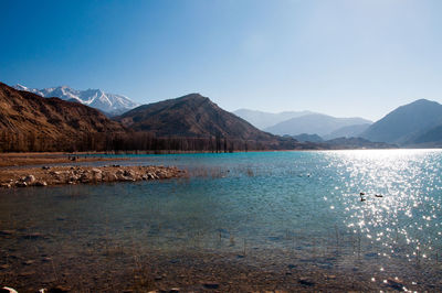 Scenic view of lake and mountains against blue sky