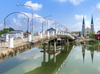 Bridge over river amidst buildings in city against sky