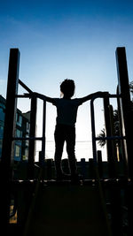 Rear view of silhouette woman standing by railing against sky