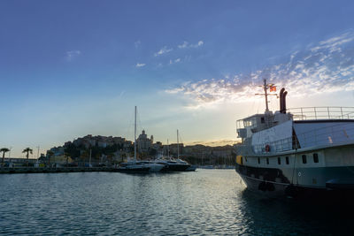 Sailboats moored on sea against sky during sunset