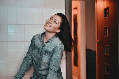 Smiling young woman standing against wall